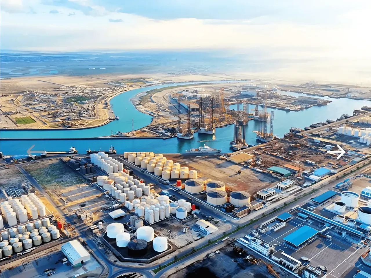 A port seen from the air: tank farms, quays and a canal leading to the sea
